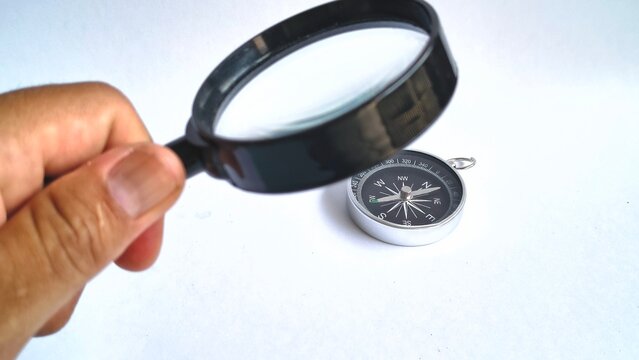 Hand Holding Magnifying Glass Inspecting Magnetic Compass Direction Concept Isolated White Background Close Up