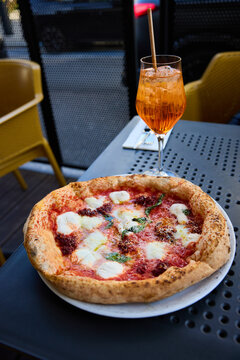 Delicious Neapolitan Pizza and Refreshing Aperol Spritz Cocktail on a Sunny Terrace