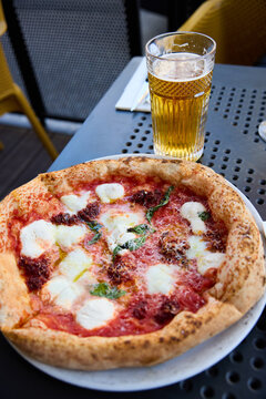 Delicious Neapolitan Pizza and Cold Beer on a Sunny Outdoor Terrace Table