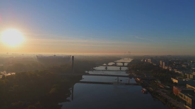 Aerial Drone Footage of Warsaw Cityscape at Sunrise featuring National Stadium, Bridges, and Vistula River