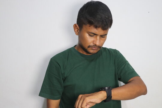Young Man Looking At His Wristwatch Wearing Green T Shirt