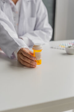 Mature Asian pharmacist show medicine bottle on table