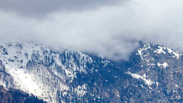 Snow-capped mountains rise beneath swirling gray clouds