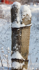 Fototapeta premium Snow blankets a weathered wooden fence post