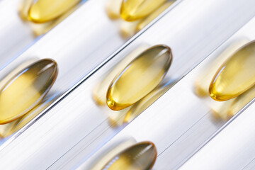 Fototapeta premium Macro golden softgel capsules arranged on conveyor for vitamin supplement packaging