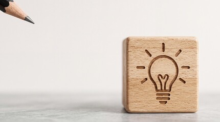 Fototapeta premium Close Up of Wooden Block with Light Bulb Icon Representing Creative Idea and Innovation, Pointed by Pencil Tip on Neutral Background for Business Brainstorming and Solution Concept