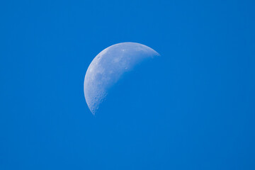 Peaceful daytime view of the crescent moon visible against a clear blue sky in Slovenia, evoking a serene and contemplative atmosphere © erikzunec