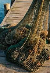 Fototapeta premium Sustainable fishing and maritime industry, commercial fishing nets piled on a wooden pier at sunset for coastal economy and marine conservation concepts