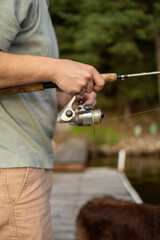 Fototapeta premium Man holds a fishing rod while standing on a dock