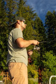 Man in sunglasses and backwards hat fishing outdoors on a sunny day