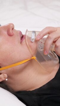 Close up of a healthcare worker applying a resuscitation mask to a female patient experiencing breathing difficulties, providing life saving oxygen therapy in a medical clinic