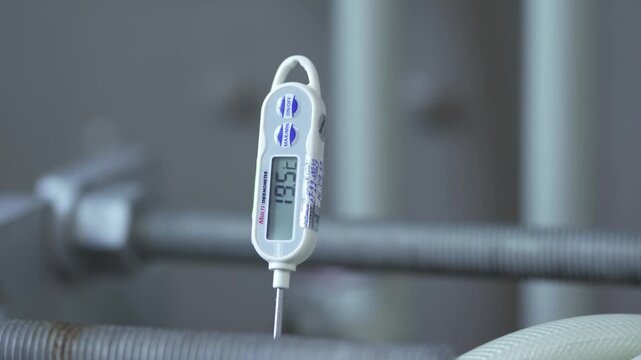 Digital thermometer measuring changing temperature in stainless steel brewery equipment, close up of industrial brewing process in a production facility