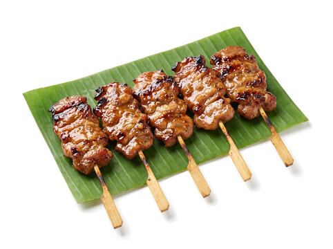 Moo ping Thai grilled pork skewers on banana leaf, isolated on white background