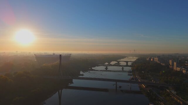 Aerial Drone Footage of Warsaw Cityscape at Sunrise featuring National Stadium, Bridges, and Vistula River