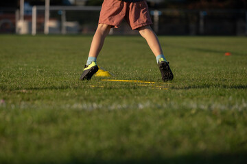 Obraz premium Child wearing football cleats during agility training drill