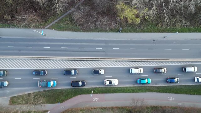 Aerial view of busy roadway showcasing dynamic traffic flow with various vehicles moving in different lanes, camera pans smoothly to capture scene progression and urban environment