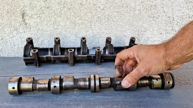 Removed engine camshaft and rocker arm assembly shown during automotive disassembly, inspection, repair, maintenance, and mechanical restoration work in a workshop