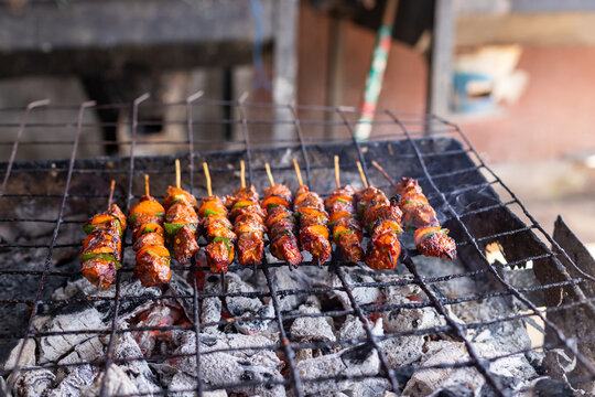 Mishikaki, Traditional Tanzanian beef skewers with carrots and green bell peppers grilling over a charcoal grill at a street food stall in Dar es Salaam, Tanzania.
