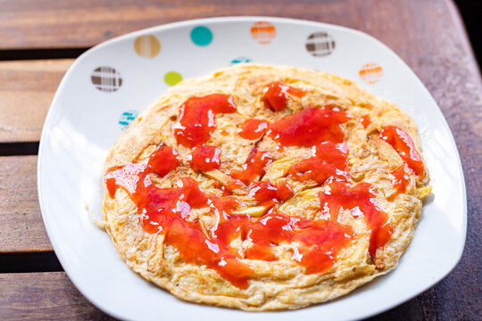 A plate of traditional Tanzanian chipsi yai (french fry omelet), also known as zege, topped with tomato ketchup and served at a local street food spot in Dar es Salaam, Tanzania.
