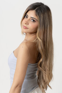 Retrato de mujer con cabello largo posando de perfil sobre fondo blanco