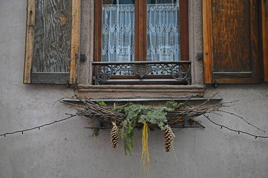 Typical Alsatian rural house window with wooden shutters and festive Christmas decorations in Bergheim, Alsace France.
