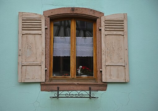Antique rural house window with wooden shutters in Bergheim, Alsace France.