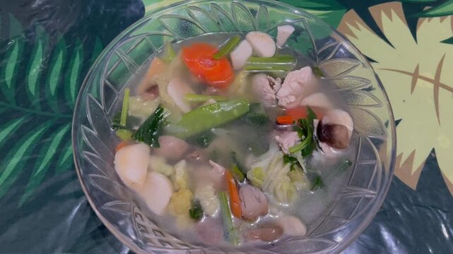 Close-up video of Indonesian capcay with mixed vegetables, presented in a bowl on a flower-patterned table.