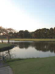 Naklejka premium Tranquil Golf Course Pond Surrounded by Trees and Green Lawns