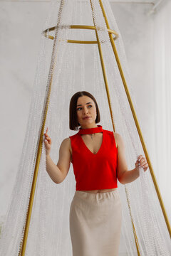 Young beautiful woman posing near gilded crystal chandelier in studio