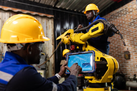 Technicians Inspecting and Maintaining an Industrial Robotic Arm with a Tablet