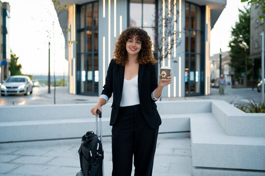 Business white woman holding coffee cup with luggage