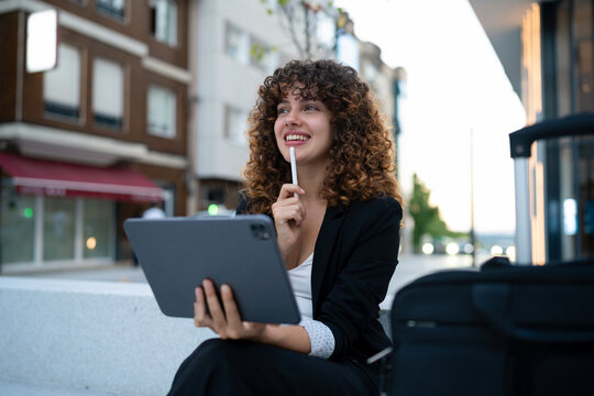 White woman holding tablet and thinking outdoors in Madrid urban area