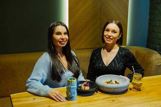 Two beautiful women are sitting at a table in a cafe