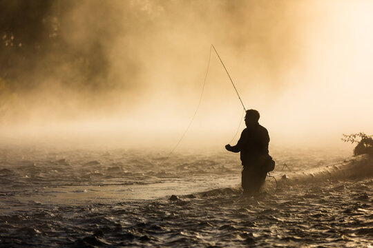 Fly fisherman casting for trout at sunrise in the Oregon fog