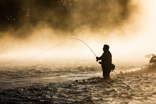 Fly fisherman casting for trout at sunrise in the Oregon fog