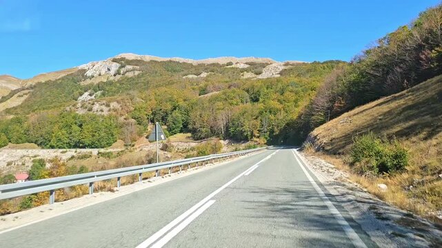 Horizontal slow motion b-roll of driving through an empty mountain asphalt road with road signs on a sunny day