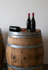 Naklejka premium Winemaking and viticulture industry, red wine bottles on a rustic wooden barrel in a winery cellar for traditional beverage production and aging process