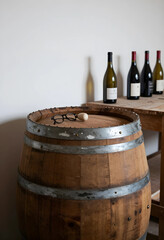Naklejka premium Winemaking and viticulture tradition, wooden wine barrel with glasses and bottles in a rustic cellar for craft beverage production and tasting events