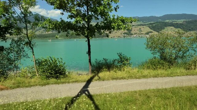 Panoramic views of a turquoise lake In The Swiss Canton Of Obwalden, Central Switzerland. Passenger POV from a moving train on the Swiss Federal Railway from Lucerne to Interlaken (Brunig Pass).
