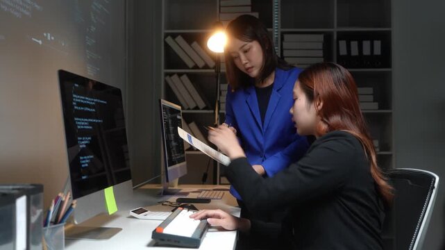 Asian female programmers collaborating on code late at night