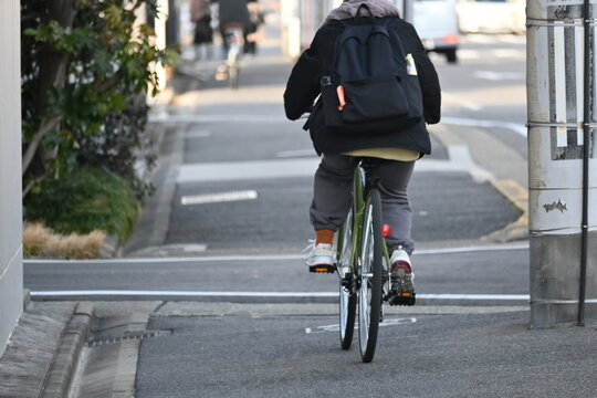 街中を自転車で走る後ろ姿の人
