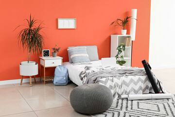 Remote learning and student lifestyle, laptop on bed in a modern bedroom with orange wall and study supplies for distance education or home office © Pixel-Shot
