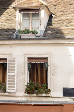 Roof dormer window decorated with blooming flowers in Paris