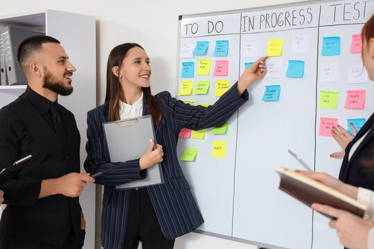 Agile project management and team collaboration, business professionals planning tasks with sticky notes on a whiteboard in a modern office environment