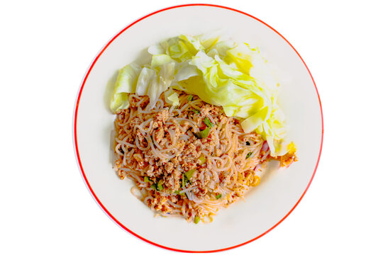 Top down view of spicy Thai rice vermicelli noodle salad with minced pork and fresh cabbage on a plate, isolated on a white background