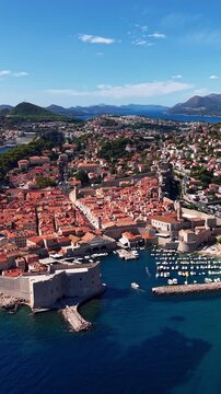 Dubrovnik, Croatia, aerial view of the historic old town, ancient city walls, harbor, and marina with boats on a sunny day, travel footage