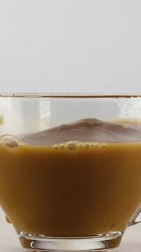 Close Up of Coffee with Milk Splashing in Clear Glass Cup