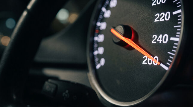 Close up of car speedometer needle pointing towards 260 kilometers per hour