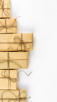 Stack of rustic kraft paper gift boxes stacked in a vertical border line over white backdrop