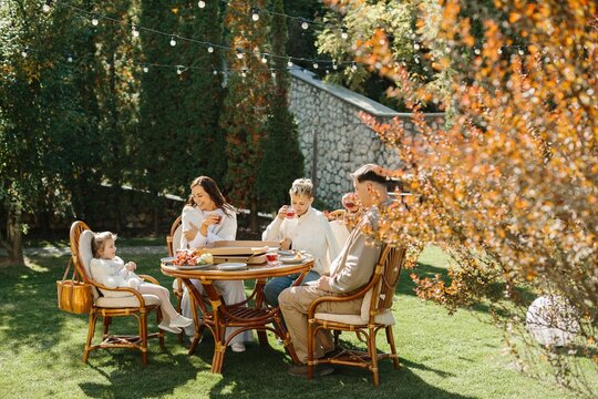 Pregnant woman and family enjoying outdoor meal in garden